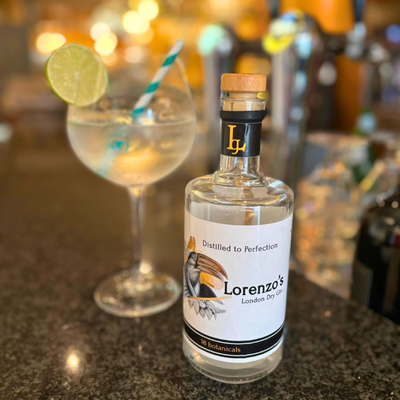 Fles van Lorenzo's Dry Gin en glas met Gin Tonic op de bar.